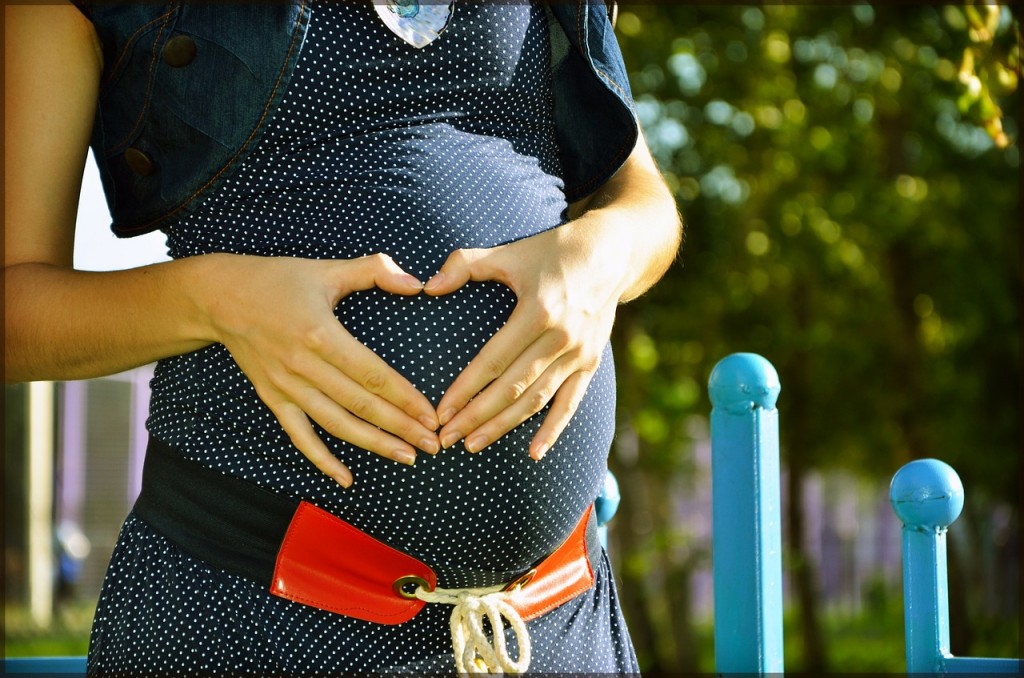 お腹の上でハートマークを作る妊婦