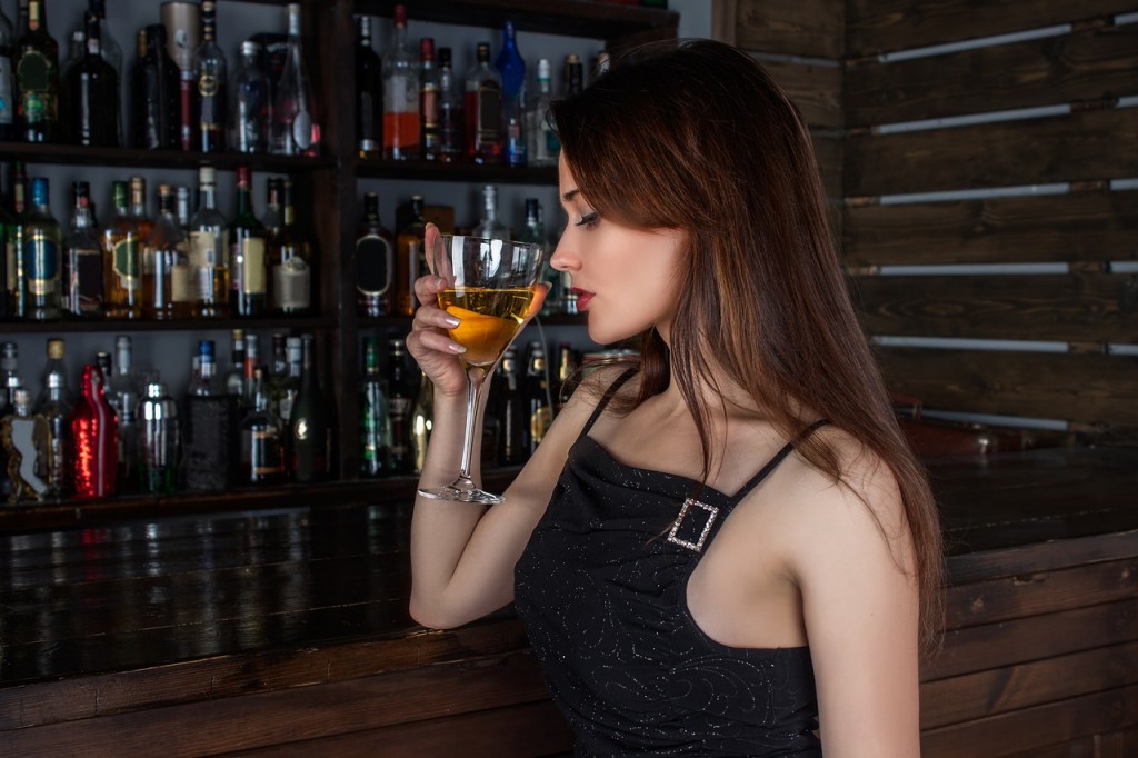 グラスに入ったウイスキーの香りを楽しんでいるドレス姿の女性